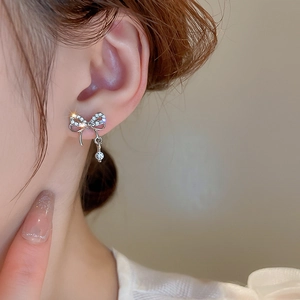 Gros plan de boucles d'oreilles nœud en argent avec cristaux sur l'oreille du mannequin