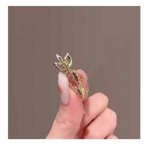 Macro view of a gold carrot brooch with inlaid pink crystal and green gemstones