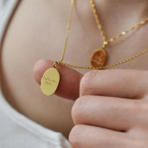 Golden oval stainless steel September Aster floral pendant necklace worn by model