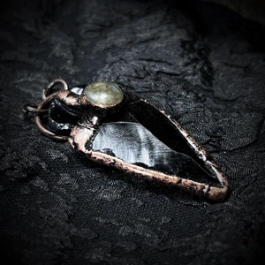 Detailed view of obsidian arrowhead pendant with bronze edging and labradorite inlay