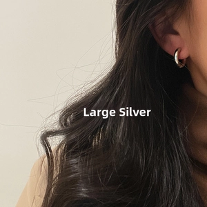 Close-up of large silver stainless steel hoop earring worn by a model in profile