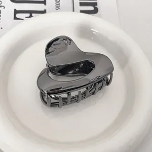 Detail of silver heart-shaped metal hair claw clip with a polished mirror finish on a plate