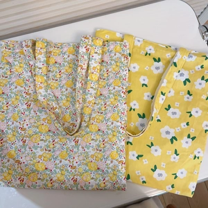 Detail view of yellow floral canvas tote bags with double-layer durable fabric texture