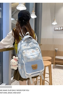 Detail of light blue plaid backpack with bear embroidery and fluffy rabbit keychain