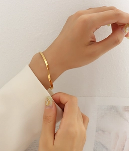 Close-up of elegant gold twisted cuff bracelet on a female wrist with soft lighting