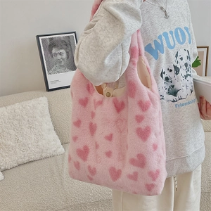 Pink plush tote bag with heart pattern shown being worn on the shoulder by a model