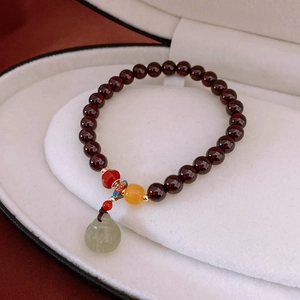Detailansicht eines Granat-Armbands mit einem hellgrünen Jade-Buddha-Anhänger-Charm