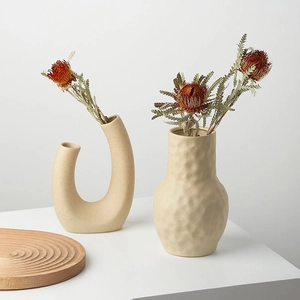 Vases minimalistes en céramique beige avec fleurs séchées, formes en U et texturées
