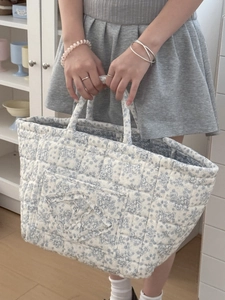 Close-up of quilted floral corduroy storage basket with blue flower patterns and handles