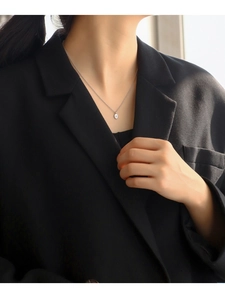 Macro detail of silver oval pendant with star engraving on model in black suit