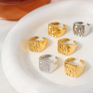 Minimalist geometric hammered open rings in gold and silver finish on ceramic plate