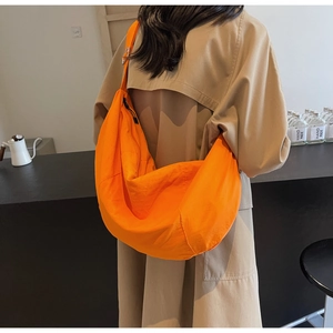 Detail view of orange nylon crossbody bag with large capacity and wide shoulder strap