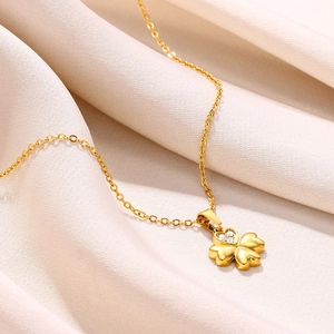 Detail of 18K gold clover necklace with heart-shaped leaf and sparkling zircon on silk