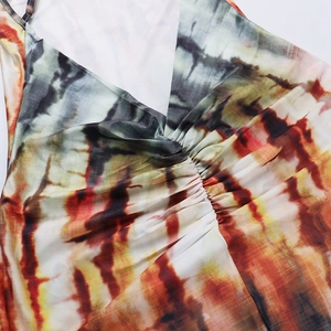 Dettaglio delle pieghe dello scollo a V sull'abito estivo tie-dye arancio e grigio