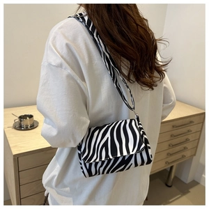 Detail view of stylish zebra print shoulder bag with wide strap on model's shoulder