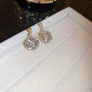 Vue macro de boucles d'oreilles fleuries plaquées or avec zircons sur un plateau en velours