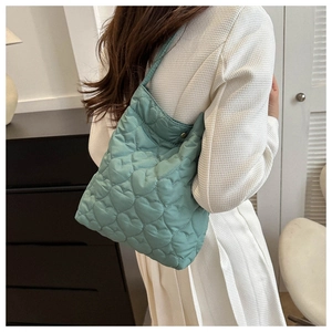 Detail of mint green quilted tote bag with heart pattern and soft nylon texture