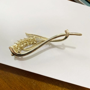 Detailed view of the wheat ear design and textured metal finish of the gold hair clip