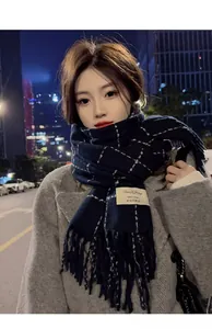 Detailed view of the dark blue checkered scarf with soft fringe and sewn brand label
