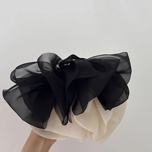 Oversized double-layered chiffon bow hair clip in black and white on hands