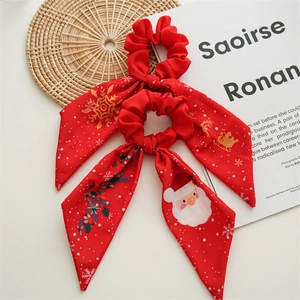 Detailed view of red Christmas scrunchie with Santa prints and a large bow design
