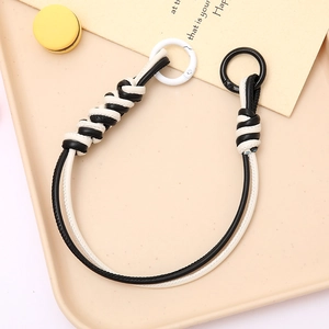Detail of hand-woven black and white leather lanyard with two circular metal buckles