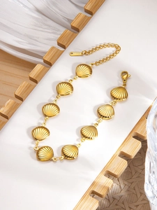 Macro shot of gold-plated stainless steel shell bracelet on a wooden display tray