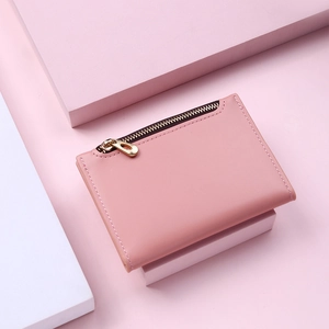 Pink short folding wallet with gold zipper detail on matching geometric pink base