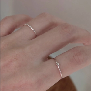 Set of two minimalist 925 sterling silver rings with knotted and beaded patterns on finger