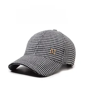 Détail d'une casquette de baseball avec motif pied-de-poule noir et blanc et logo M doré