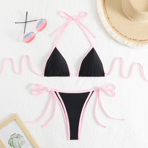 Flat lay of pink and black bikini set with straw hat and sunglasses for summer beach holiday