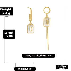 Detail showing asymmetric gold earrings with white acrylic, crystals and 925 silver needles