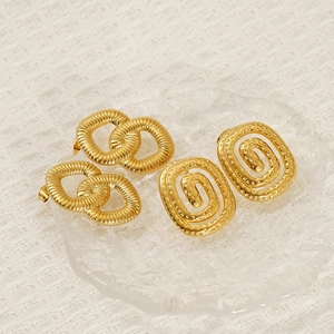 Gold-plated stainless steel interlocking rings and spiral stud earrings on glass tray
