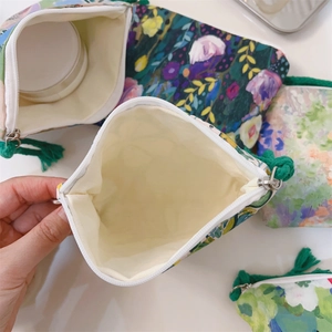 Detail of oil painting floral canvas pouch with metal zipper and decorative green rope puller