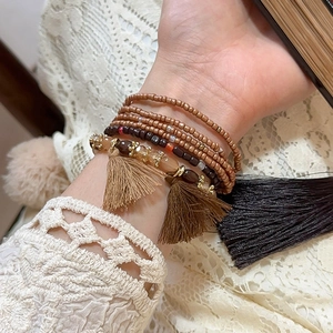 Detail of bohemian multilayered bead bracelet with tassels and crystal accents on wrist