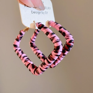 Gros plan de boucles d'oreilles carrées avec motif zèbre rose et noir en tissu doux