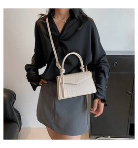 Vertical pleated cream shoulder bag shown on model with knot detail and slim strap