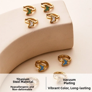 Detail of gold titanium steel butterfly hoop earrings with white green and blue enamel charms