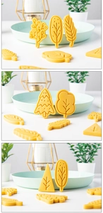 Macro shot of yellow plastic Christmas tree cookie molds and finished leaf biscuits