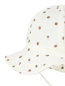 Detailed macro view of cream cotton baby sun hat with brown polka dots and white tie