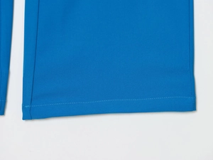 Macro de l'ourlet du blazer bleu montrant la texture du sergé et les coutures précises