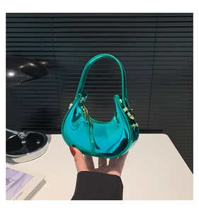 Detail of glossy green patent leather handbag featuring a crescent shape and gold hardware