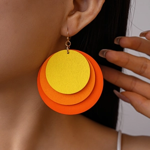 Close-up of triple-layered geometric round wooden earrings in yellow and orange on model