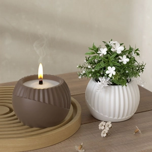 Spherical striped aroma candle on wooden tray with white textured plant pot ornament
