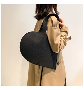 Detail of a chic black felt heart-shaped handbag styled with a khaki trench coat