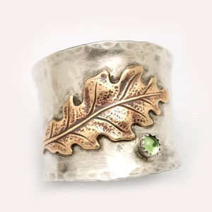 Silver wide ring with golden leaf and green gemstone featuring hammered metal texture