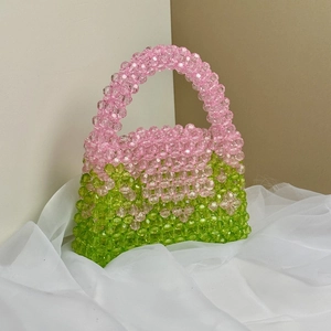 Close-up of handmade beaded handbag with pink and green gradient on white silk fabric