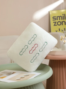 Detailed view of Mahjong-themed white plush pillow with 5-dot embroidery on a tray