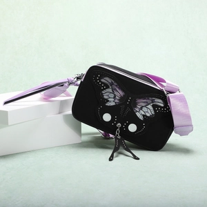 Detail of black matte crossbody bag with butterfly wing prints and purple strap