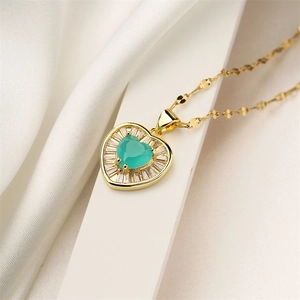 Detailed view of golden heart pendant with green gemstone on white silk background